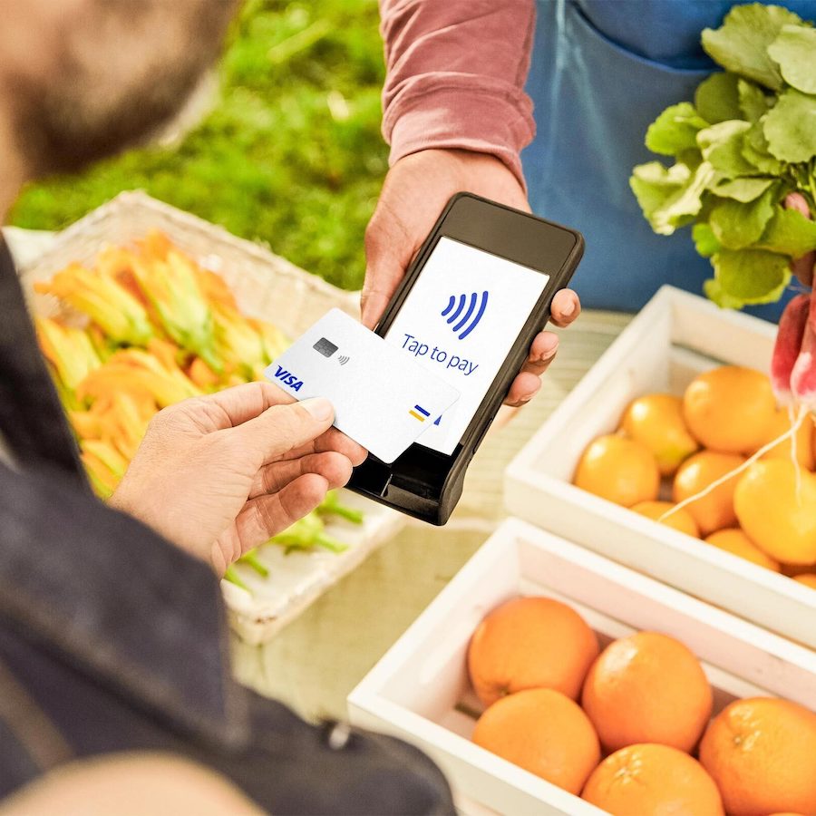person buying fruit with their visa card using contactless